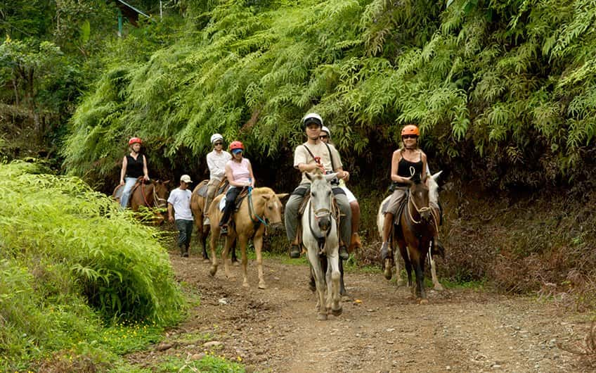 six people horseback riding inside the rainforest at Manuel Antonio National Park