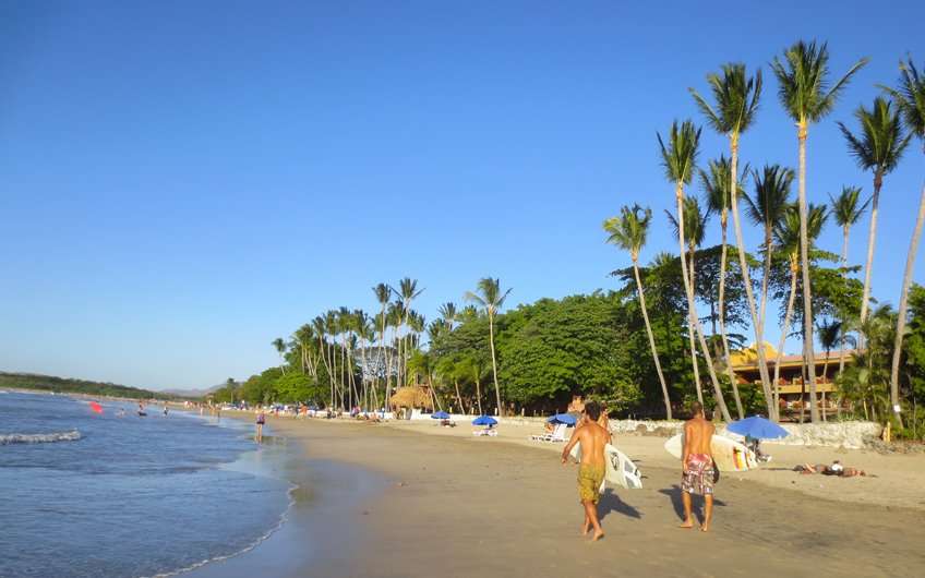 Two surfers walking on Tamarindo beach looking for some morning waves