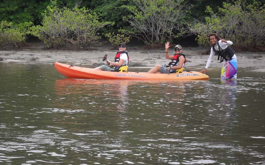 A couple of tourists posing for a picture with their tour guide while kayaking.