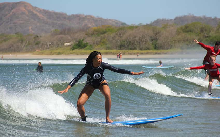 A woman trying to balance on the board during her surf lessons.