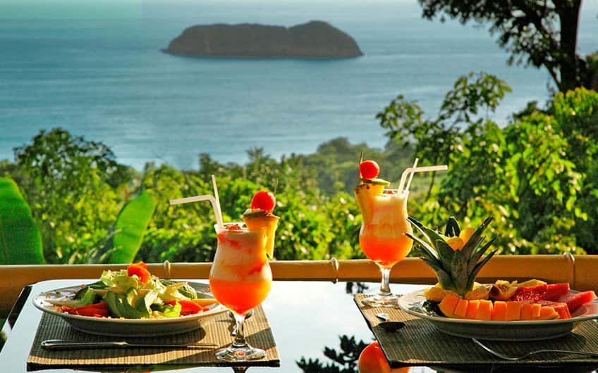 A lunch for two is served overlooking the ocean from a hill.