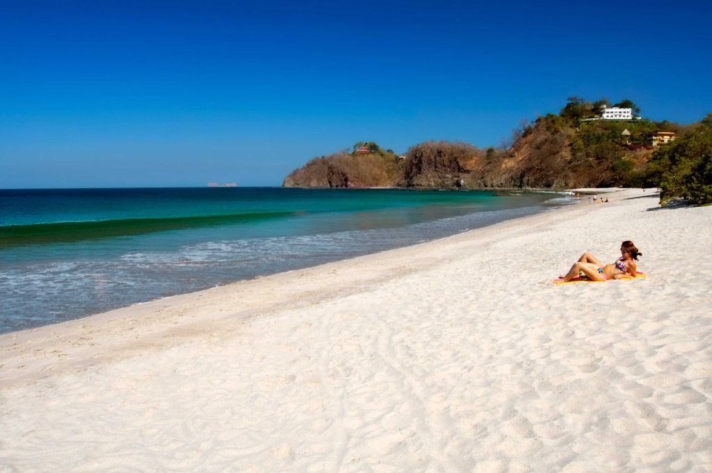 A couple enjoying flamingo beach in guanacaste lying on the sand in their costa rica vacations